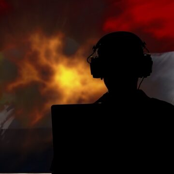 Concept Image Of A Silhouette Of A Person Wearing Headphones, Looking At A Screen, Against A Backdrop Of An Explosion And A Flag Resembling The Flag Of Yemen