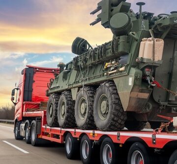 Back View Of U.S. Army Stryker Armored Personnel Carrier Being Transported On A Flatbed Truck