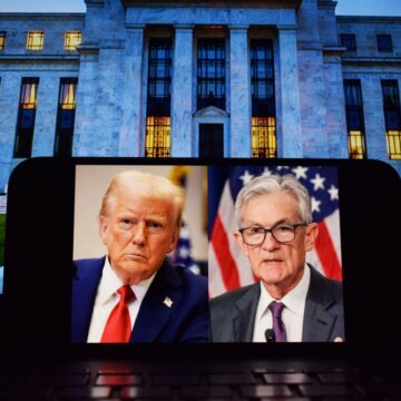 Portraits Of Donald Trump And Jerome Powell, Side-By-Side, On A Mobile Phone Screen Sitting In Front Of The U.S. Federal Reserve Building