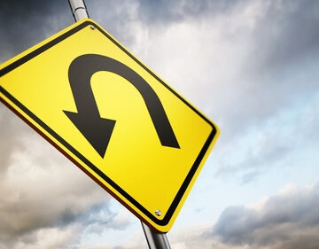 A Yellow U-Turn Sign Against A Stormy Sky