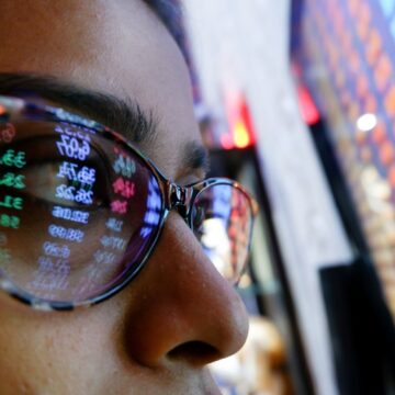 A Woman In Sunglasses Watches Stock Market Data