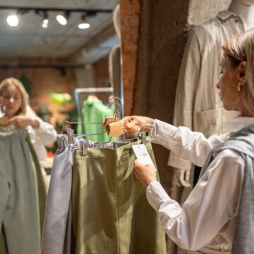 Female Retail Shopper Examining Price Ticket In Clothing Store