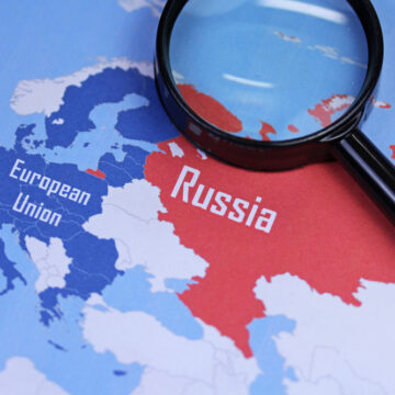 The Image Shows A Map Of Europe With The European Union And Russia Highlighted And Viewed Through A Magnifying Glass