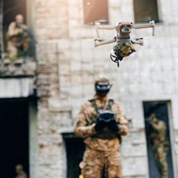 A Soldier In A Conflict Setting Operates An Armed Military Drone