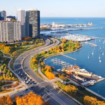 An Aerial View Of The Chicago Skyline Along The Shore Of Lake Michigan During The Autumn Season With A Marina Filled With Sailboats And Parks