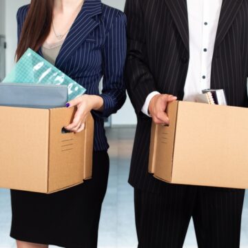 Laid Off Male And Female Business People Leaving The Office With Their Possessions In Boxes