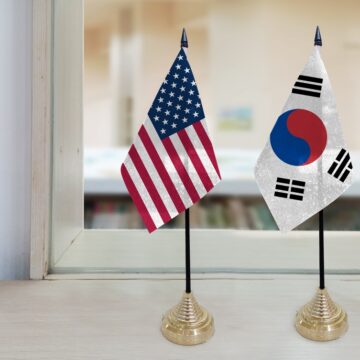 The National Flags Of The United States And South Korea Displayed Together ON A Window Sill