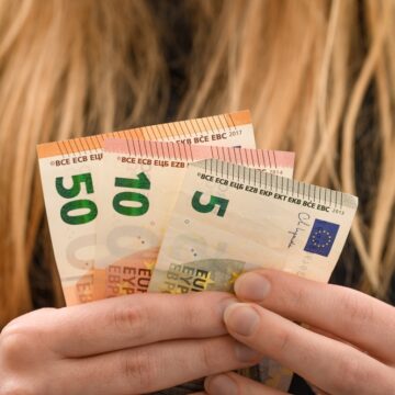 A Woman Holds A Fan Of Europa Series Euro Banknotes In €5, €10, and €50 Denominations A Woman Holds A Fan Of Europa Series Euro Banknotes In €5, €10, and €50 Denominations