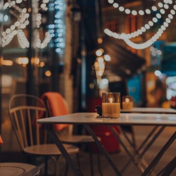 An Empty Outdoor Dining Area At A Restaurant Featuring Lit Candles And String Lights