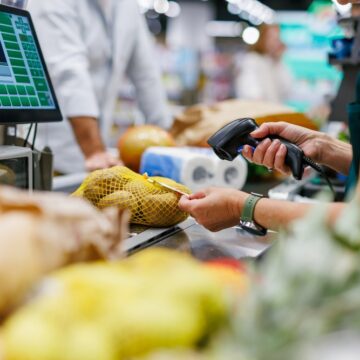 A Supermarket Cashier Scanning Produce At The Checkout Counter