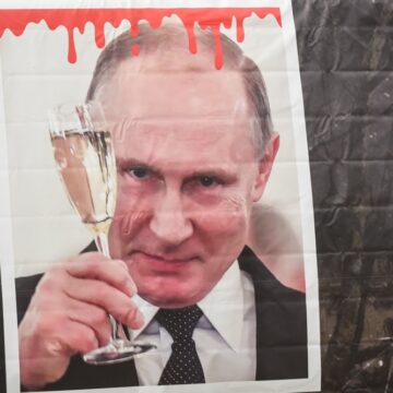 Protest Art On A Concrete Wall In Riga, Latvia, Featuring Russian President Vladimir Putin Holding A Champagne Glass Of Red Liquid Dripping From The Top, And A Rocket With The Russian Flag In The Background