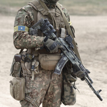 Soldier Wearing A Patch Of The Flag Of Somalia On His Right Shoulder And Carrying A Machine Gun. The Flag Patch Is Worn In The "Reverse" Orientation Which Is A Common Military Practice Designed To Give The Effect Of The Flag Flying In The Breeze As The Wearer Moves Forward Into Battle Representing Bravery And Forward Momentum