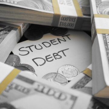 Image Features A Note That Reads "STUDENT DEBT" Surrounded By Stacks Of Money, $100 Bills Bundled in $10,000 Increments, And Some Coins
