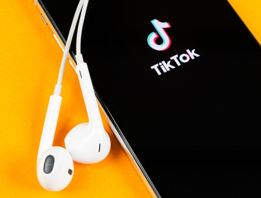 The TikTok Logo On A Mobile Phone Next To A Pair Of AirPods The TikTok Logo On A Mobile Phone Next To A Pair Of AirPods