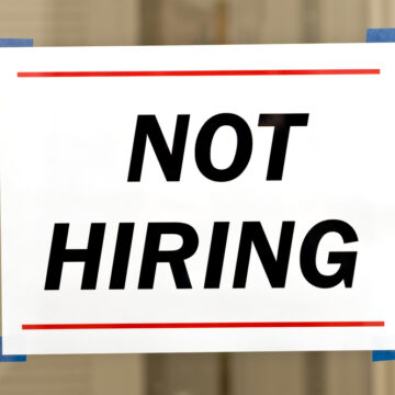 A White Sign On A Wooden Door With Large Black Capital Letters That Read "Not Hiring"
