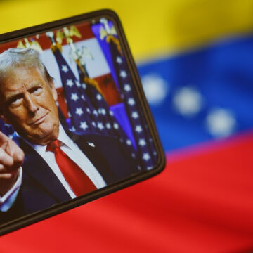 Digital Image Of Donald Trump On A Mobile Phone Pointing With The Venezuelan National Flag In The Background
