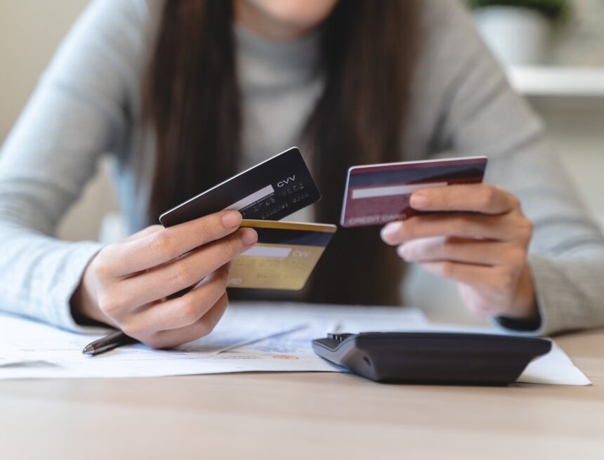 An image of a woman sitting at a table holding multiple credit cards.