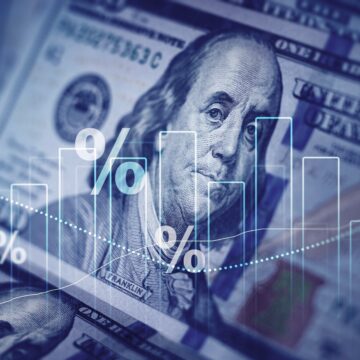 Digital image of U.S. dollar bills overlaid financial data symbols such as bar graphs and percentage symbols.