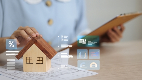 Real estate concept featuring a person presenting a miniature model house sitting atop a floor plan, and a digital interface which includes holographic data displays showcasing financial metrics.