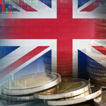 Concept graphic showing the Union Jack (the national flag of the UK) with several financial elements such as stacked coins–the British Pound Sterling – and graphs and charts.