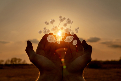 A close up of hands cupped together, showcasing a glowing, digital-style molecular structure, a concept often used to illustrate molecular physics, biochemistry, or technological connection in medicine.