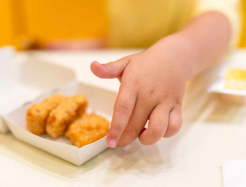 A,Small,Child,Wearing,A,Yellow,Shirt,Is,Eating,Chicken CHILDREN FACE HIGHER FOOD ADDITIVE BURDEN THAN ADULTS, EXPERTS SAY