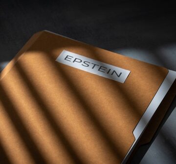 A file folder labeled "EPSTEIN" on a dark surface and in the shadows. A file folder labeled "EPSTEIN" on a dark surface and in the shadows.