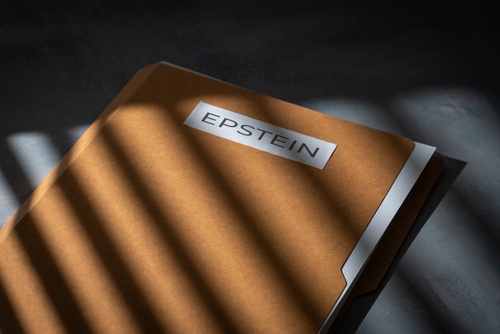 A file folder labeled "EPSTEIN" on a dark surface and in the shadows.