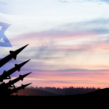 A composite graphic depicting a missile defense system, likely Israel's Iron Dome, silhouetted against a sunset sky with the Israeli flag superimposed in the sky. A composite graphic depicting a missile defense system, likely Israel's Iron Dome, silhouetted against a sunset sky with the Israeli flag superimposed in the sky.
