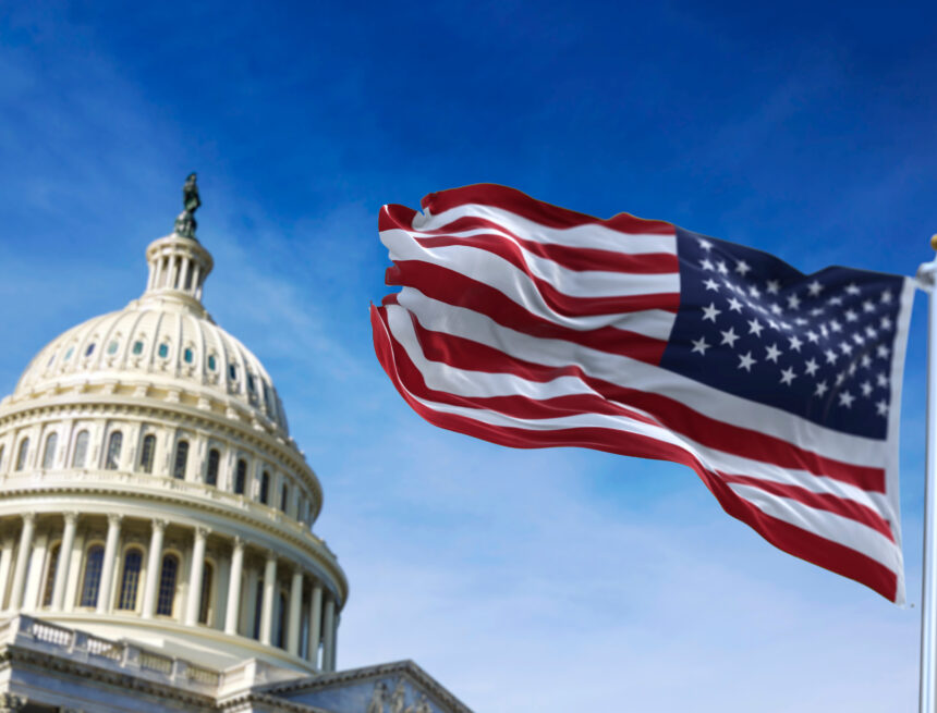 A photo of the U.S. Capitol Building dome with the American flag waving in the foreground. A photo of the U.S. Capitol Building dome with the American flag waving in the foreground.