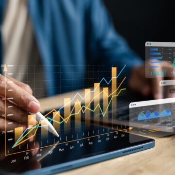Image of a person analyzing a heads-up type display of financial charts and investment graphs on a tablet screen using a stylus to interact with digital graphs and charts displayed on the tablet. Image of a person analyzing a heads-up type display of financial charts and investment graphs on a tablet screen using a stylus to interact with digital graphs and charts displayed on the tablet.