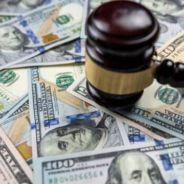 A gavel rests on a pile of U.S. currency, symbolizing the intersection of law and finance. A gavel rests on a pile of U.S. currency, symbolizing the intersection of law and finance.