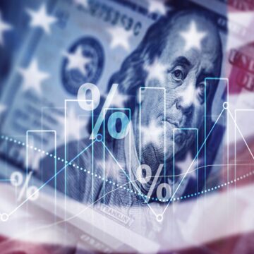 A concept graphic which features an overlay of the U.S. flag, a U.S. hundred-dollar bill, percentage symbols, and a bar/line graph suggesting a focus on the American economy.