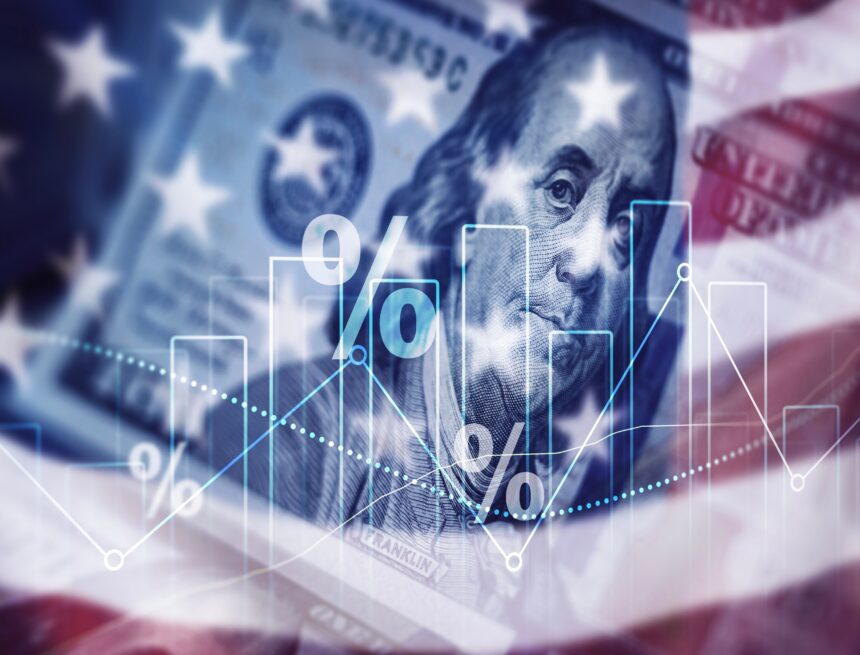 A concept graphic which features an overlay of the U.S. flag, a U.S. hundred-dollar bill, percentage symbols, and a bar/line graph suggesting a focus on the American economy.