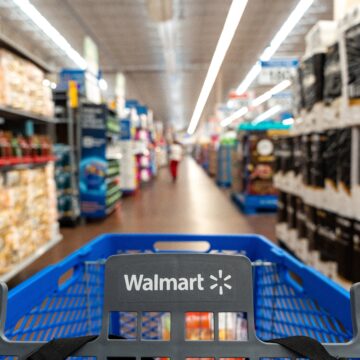 First-person view of a Walmart shopping cart being pushed down an aisle in a Walmart store.