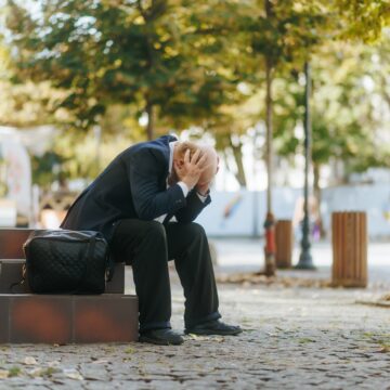 An,Elderly,Man,In,Formal,Suit,Sits,On,Stairs,,Covering WHEN THE ECONOMY FALLS, JOBS GO WITH IT