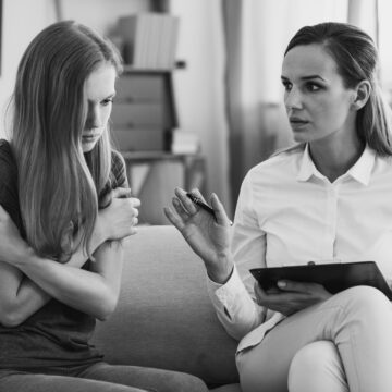 A black and white photo of a professional mental health counselor working with a distressed young person focused on mental health and emotional well-being. A black and white photo of a professional mental health counselor working with a distressed young person focused on mental health and emotional well-being.