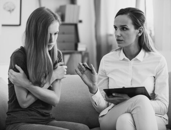 A black and white photo of a professional mental health counselor working with a distressed young person focused on mental health and emotional well-being.
