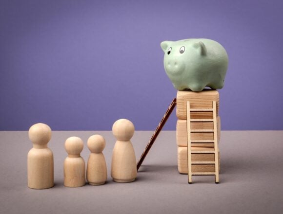 A Green Piggy Bank Sits Atop Stacked Wooden Blocks, Symbolizing A Goal Or Accumulated Savings, And A Small Ladder And Ramp Leading Up To The Piggy Bank, Suggesting A Path To Reach The Savings.