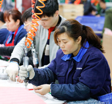 Chinese factory workers assembling components on an assembly line in a manufacturing environment in Jiangxi province, China.