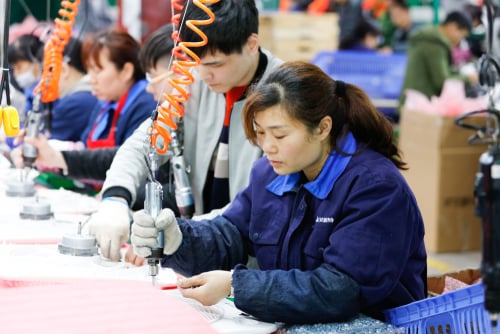 Chinese factory workers assembling components on an assembly line in a manufacturing environment in Jiangxi province, China.