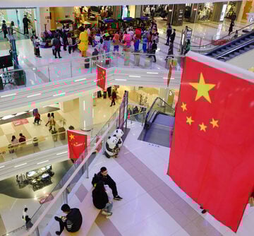 A large shopping mall in Shanghai, China, decorated for National Day with the Chinese national flag prominently displayed in the center.