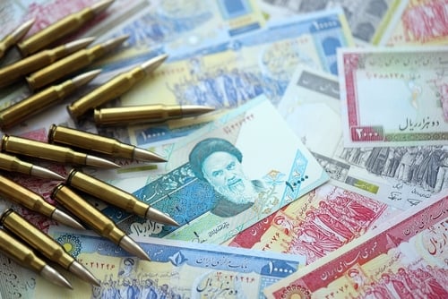 A collection of ammunition rounds arranged alongside various denominations of Iranian rial banknotes.