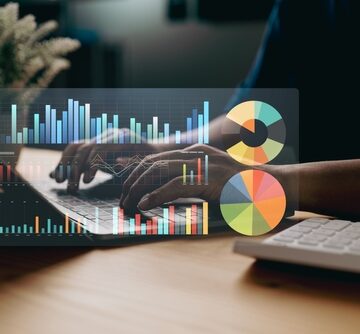 A person working on a laptop with a digital overlay of various charts, including bar graphs and pie charts.
