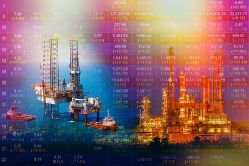 A double exposure photo that combines an aerial view of an offshore oil rig platform in a gulf with a digital overlay of stock market price changes.