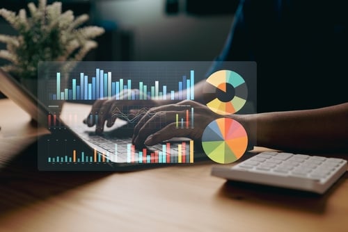 A business data analysis concept where a person is using a computer to review data, summarize information, and create reports for strategic planning.
