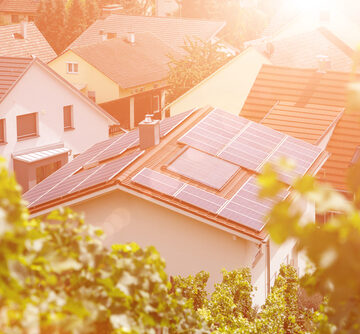 An aerial view of residential homes featuring rooftop solar photovoltaic (PV) panels designed to capture sunlight and convert it into electricity. 