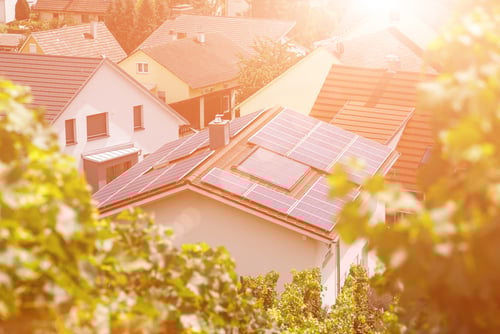 An aerial view of residential homes featuring rooftop solar photovoltaic (PV) panels designed to capture sunlight and convert it into electricity. 