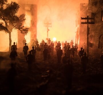 An apocalyptic view of a city featuring silhouettes of soldiers marching against a background is filled with fire, smoke, and a bright explosion. An apocalyptic view of a city featuring silhouettes of soldiers marching against a background is filled with fire, smoke, and a bright explosion.
