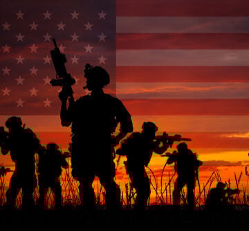 Silhouette of military soldiers with weapons against a brilliant red sunset